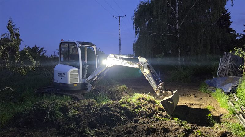 Minikoparka podczas prac ziemnych po zmroku